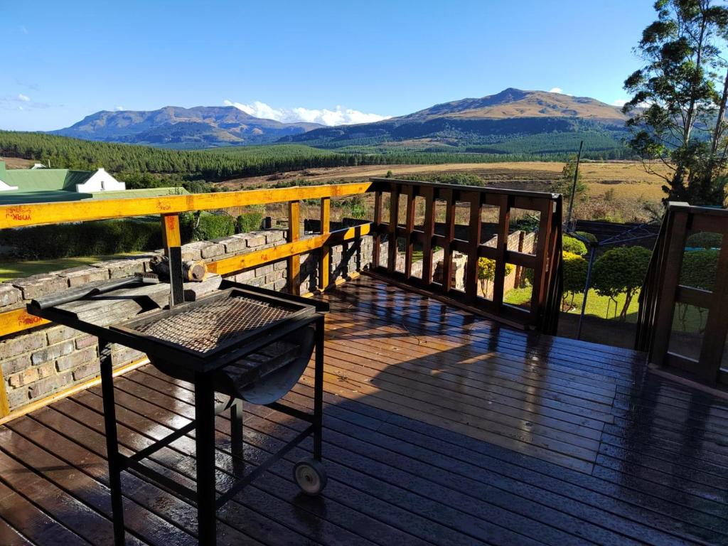 a wooden deck with a bench and mountains in the background at Boh- House in Graskop