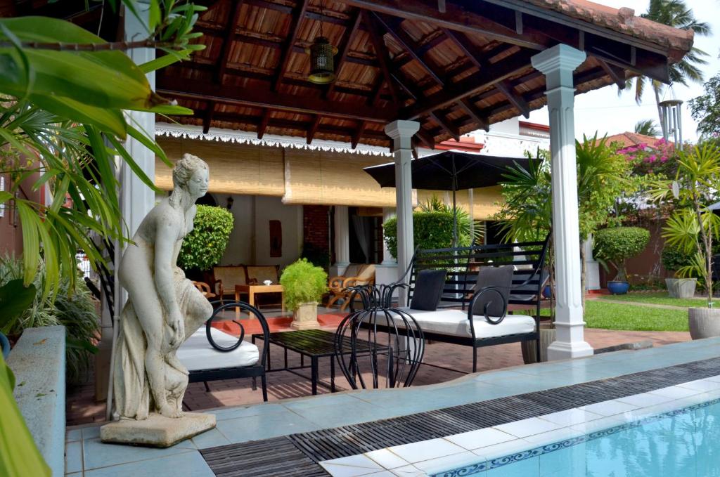uma estátua de uma mulher ao lado de uma piscina em Ayubowan Guesthouse em Negombo