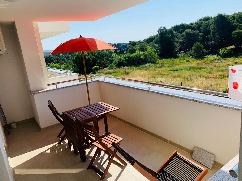 balkon ze stołem, krzesłami i parasolem w obiekcie Fisherman's apartment w mieście Premantura