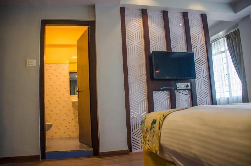 una camera con letto e TV a schermo piatto di Olive By Tej Hotel And Resorts a Darjeeling