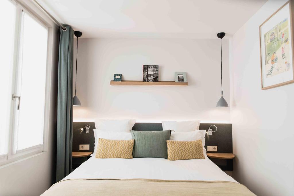 a bedroom with a bed with pillows and a window at Victoire & Germain in Paris