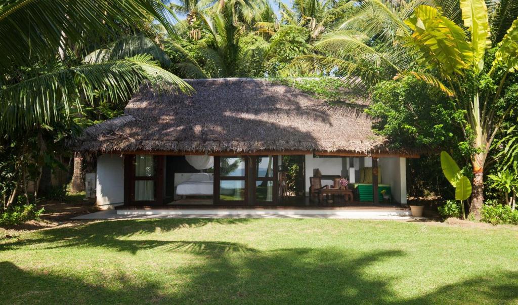 a small house with a thatched roof and a yard at Koyao Island Resort in Ko Yao Noi