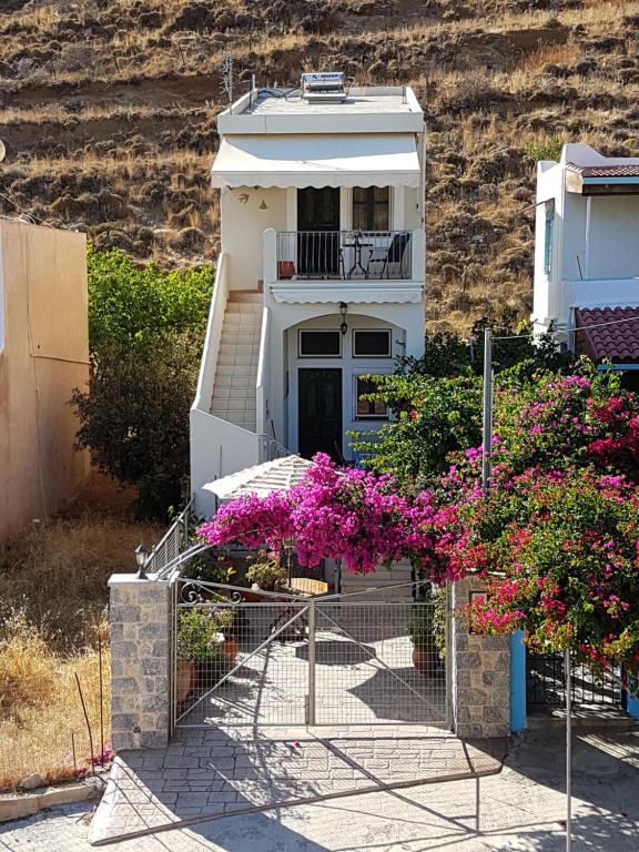 una casa blanca con flores rosas delante en Seaside Apartment 2, en Emborios