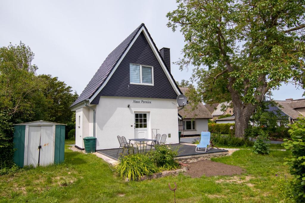 uma casa branca com um telhado preto e um pátio em Ferienhaus Pernice em Freest