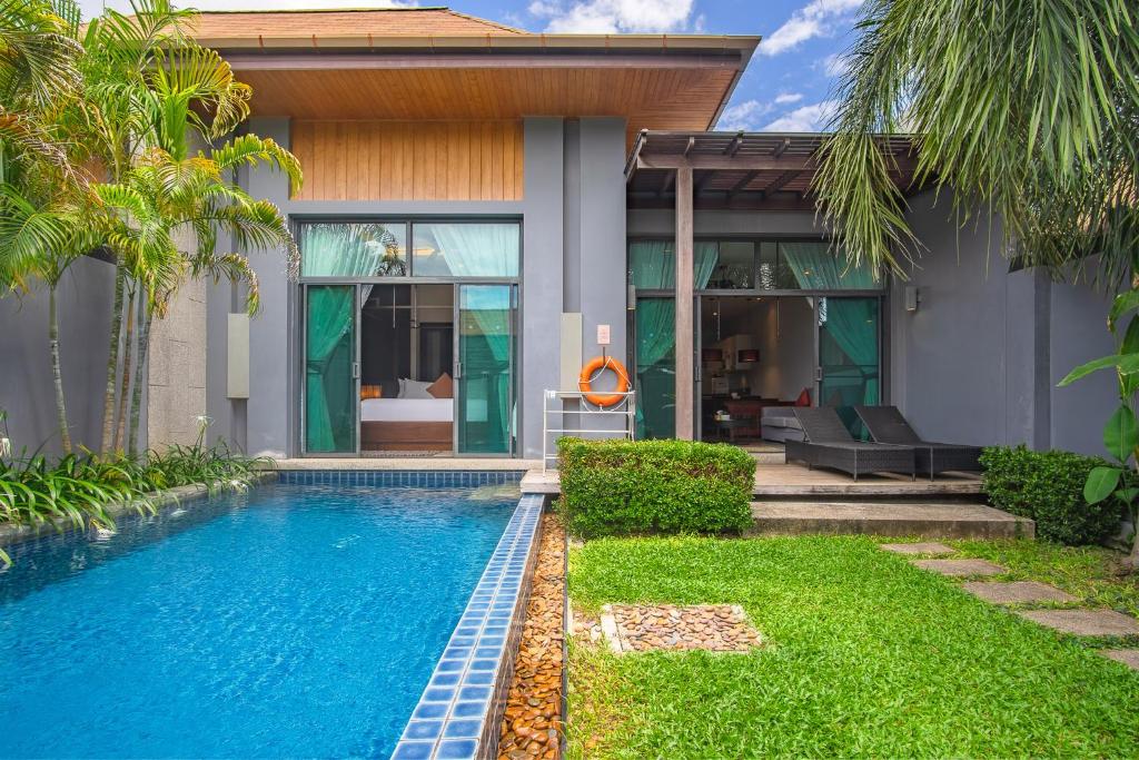 a villa with a swimming pool in front of a house at Two Bedroom Onyx Villa Nai Harn in Nai Harn Beach