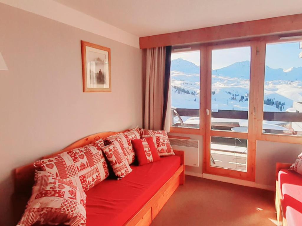 - un salon avec un canapé rouge et une grande fenêtre dans l'établissement Beau studio 4 pers, pied des pistes, balcon, casier à skis - FR-1-181-2137, à La Plagne Tarentaise