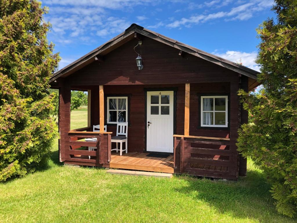 eine Holzhütte mit einer Terrasse und einer weißen Tür in der Unterkunft Merejussi Puhkemajad in Pärna