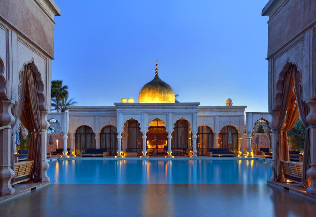 une grande cour avec une piscine en face d'un bâtiment dans l'établissement Palais Namaskar, à Marrakech