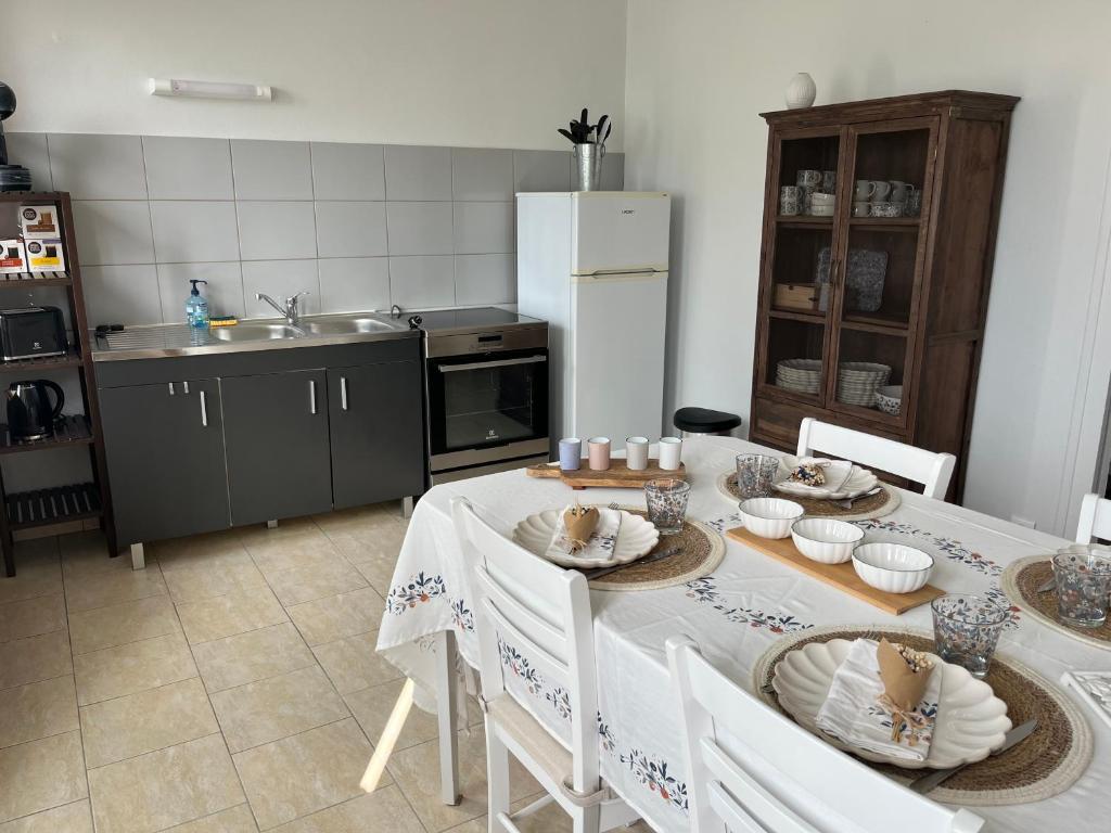 een keuken met een tafel met stoelen en een koelkast bij Maison au coeur du Morvan in Arleuf