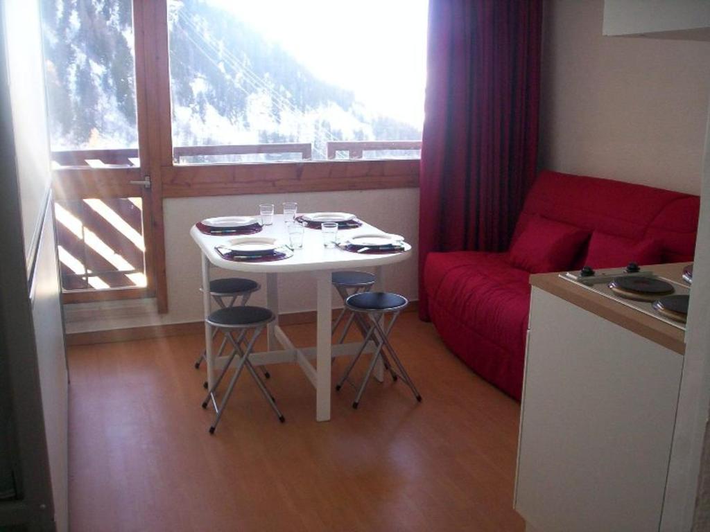 a small kitchen with a table and chairs and a window at Studio Plagne Bellecôte, 1 pièce, 2 personnes - FR-1-181-2234 in La Plagne Tarentaise