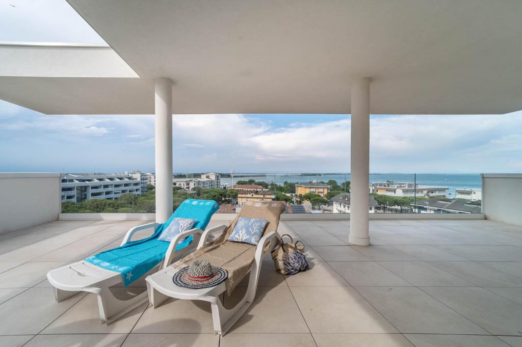 a balcony with two lounge chairs and a view of the ocean at Zero5.Zero5 in Lignano Sabbiadoro