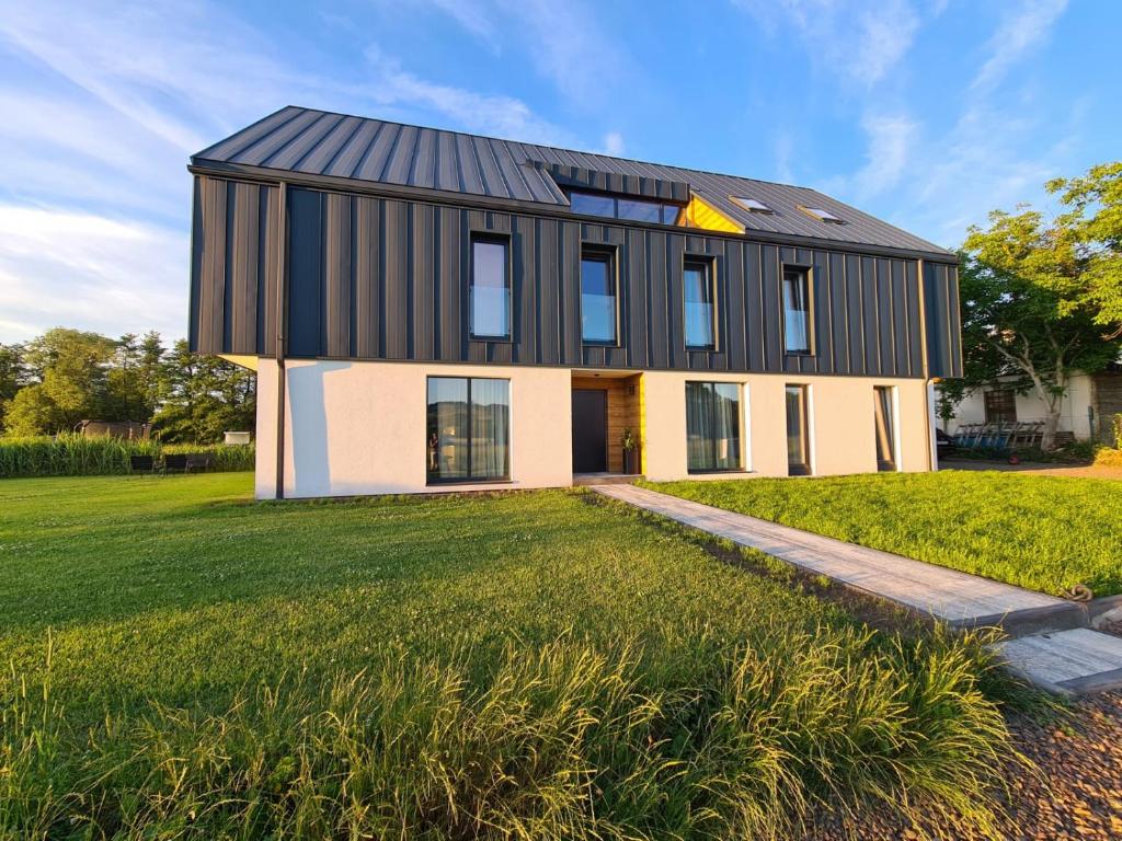 a black and white house on a grassy field at Apartamenty Boczna 3B z sauną i balią in Kudowa-Zdrój
