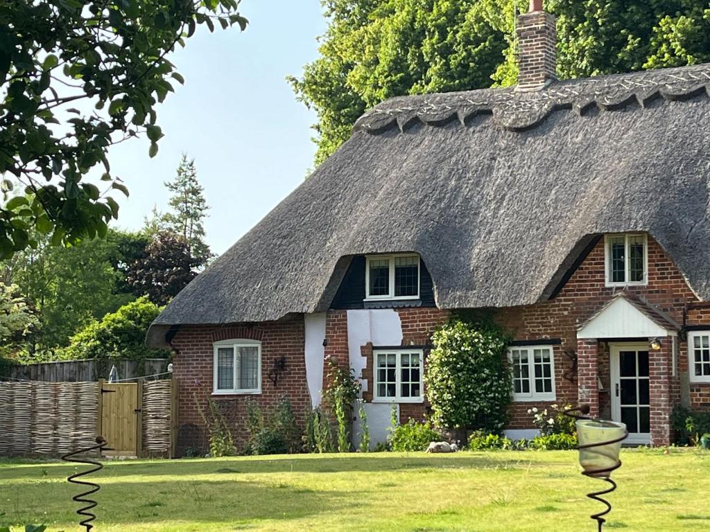 an old brick house with a thatched roof at Jasmine Cottage in Iwerne Minster