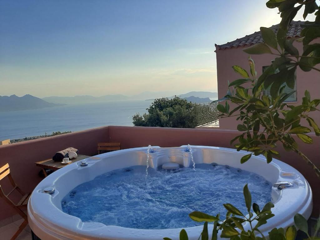 a hot tub on a balcony with a view of the ocean at Aegina Colors in Sfendoúrion
