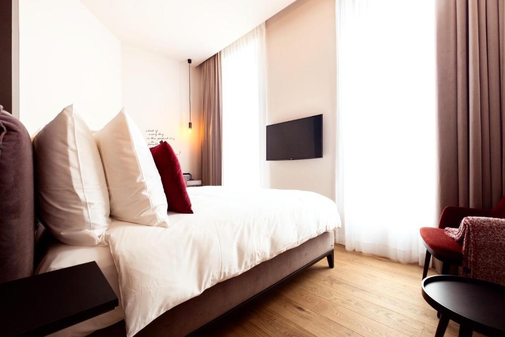 a bedroom with a white bed with a red pillow at U Eat & Sleep Antwerp in Antwerp