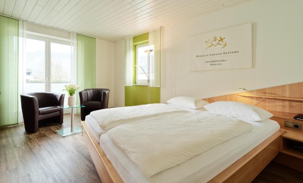 una camera con un grande letto bianco e una sedia di Kettern Urlaub a Piesport