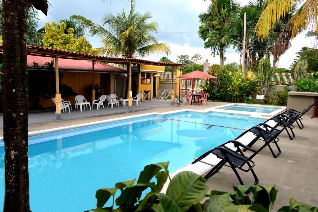 une grande piscine avec des chaises et une maison dans l'établissement Cabañas Yakuruna, à Leticia