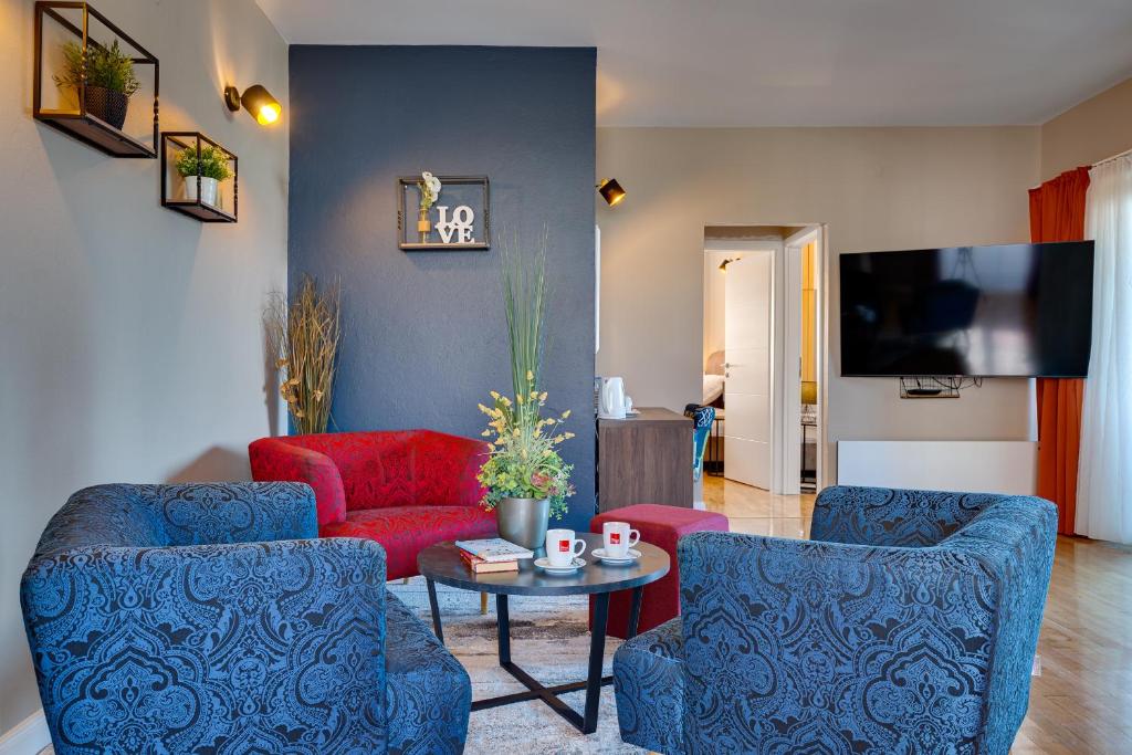 a living room with two blue chairs and a red couch at Hotel Sky in Zadar