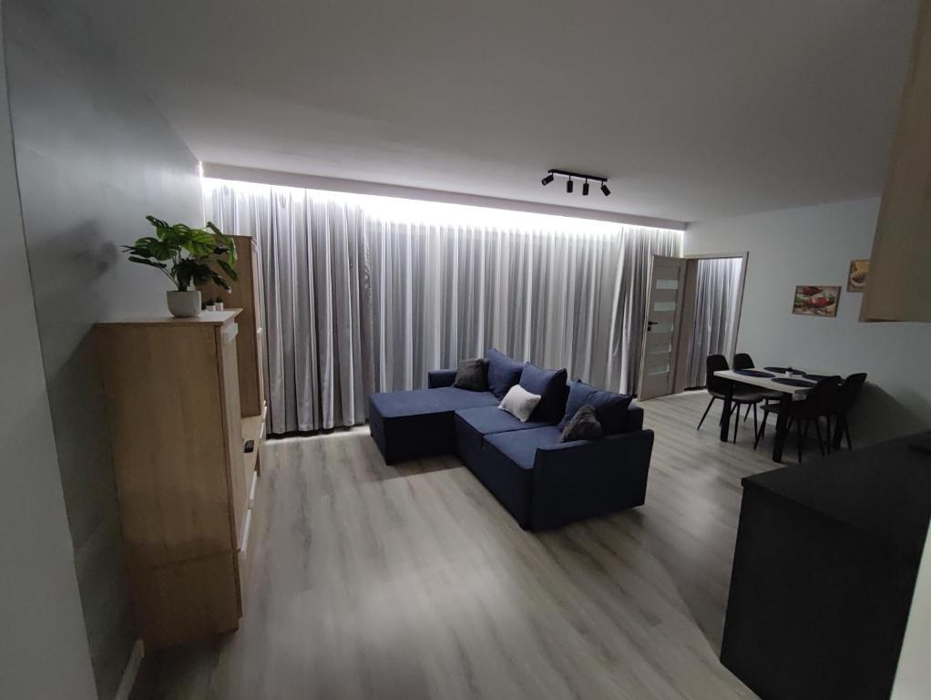 a living room with a blue couch and a table at Apartament Bukowy in Wejherowo