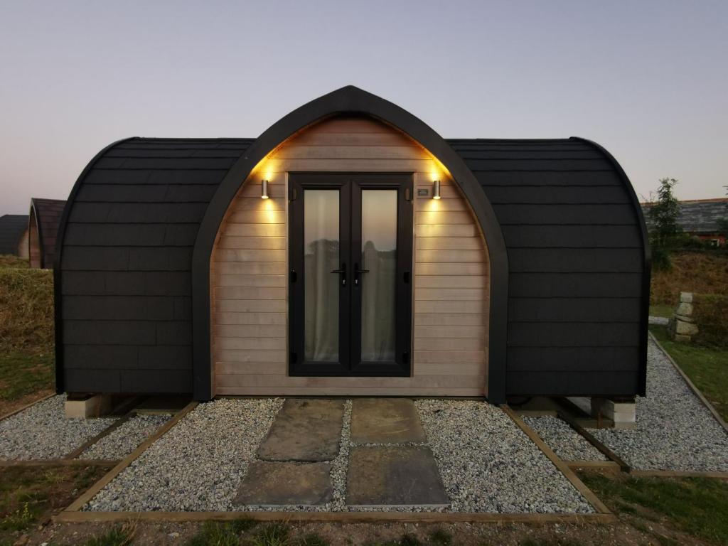 a lean to shed with a door and a window at Glamping Pods Nr Port Isaac in Port Isaac