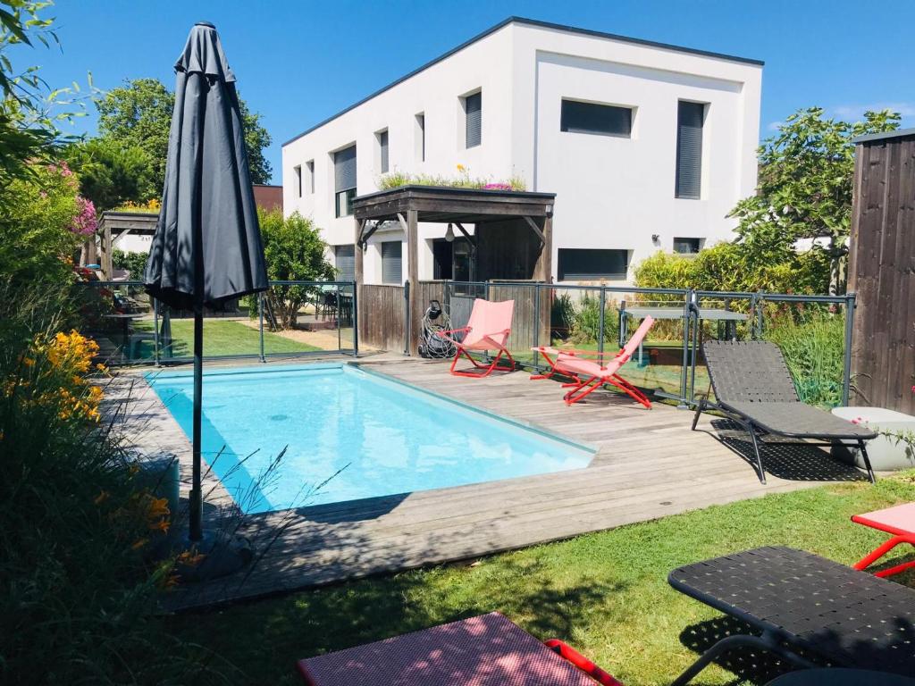 un patio trasero con piscina y sombrilla en Villa 12 PERS - PISCINE, en Les Sables-dʼOlonne