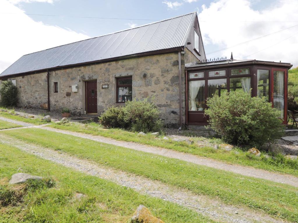 a stone house with a glass door and a gravel road at Blairgorm Croft in Nethy Bridge