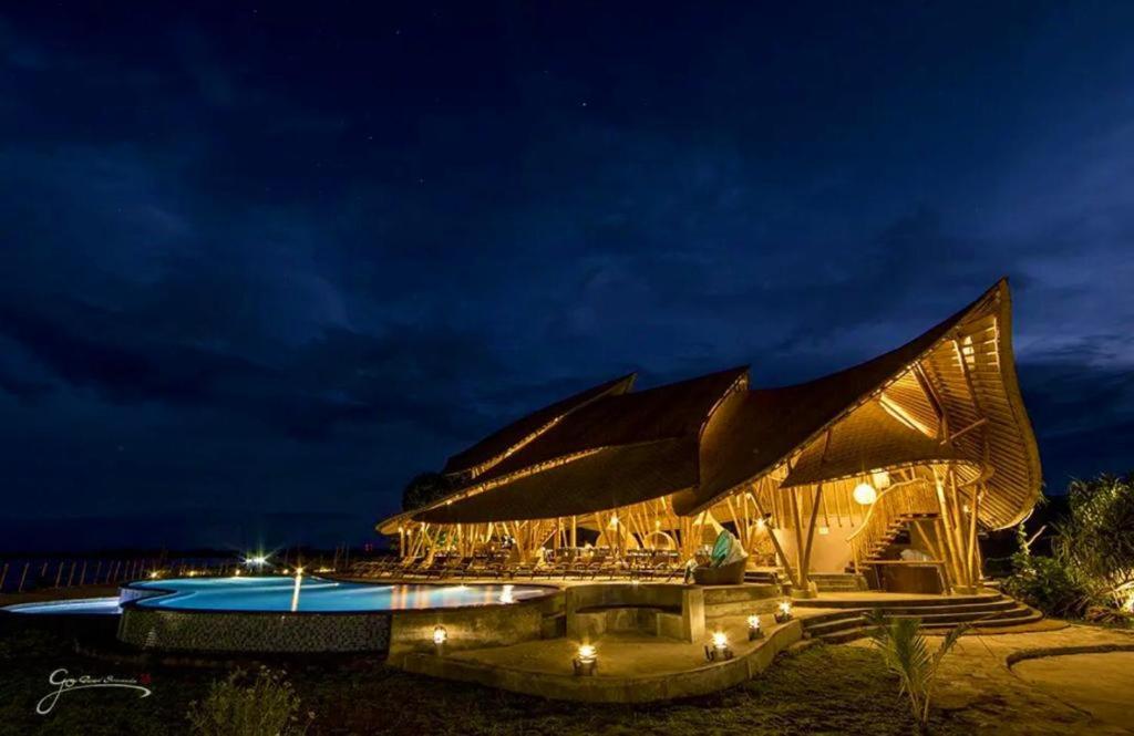 a large building with a swimming pool at night at Tanoma Sumba in Maujawa