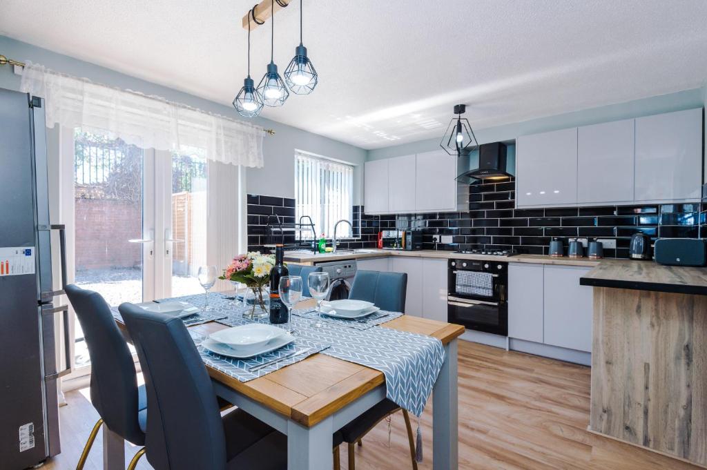 a kitchen with a table and chairs and a kitchen with white cabinets at Stylish 4 bedroom home close to Manchester City centre in Manchester