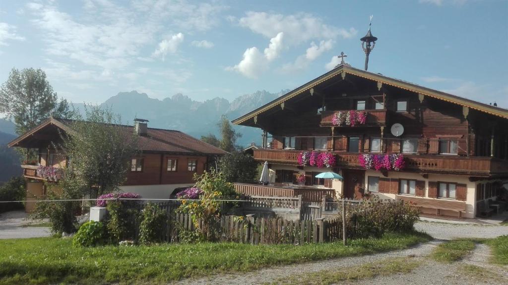 ein großes Holzhaus mit Blumen auf dem Balkon in der Unterkunft Schießling Hof in Oberndorf in Tirol
