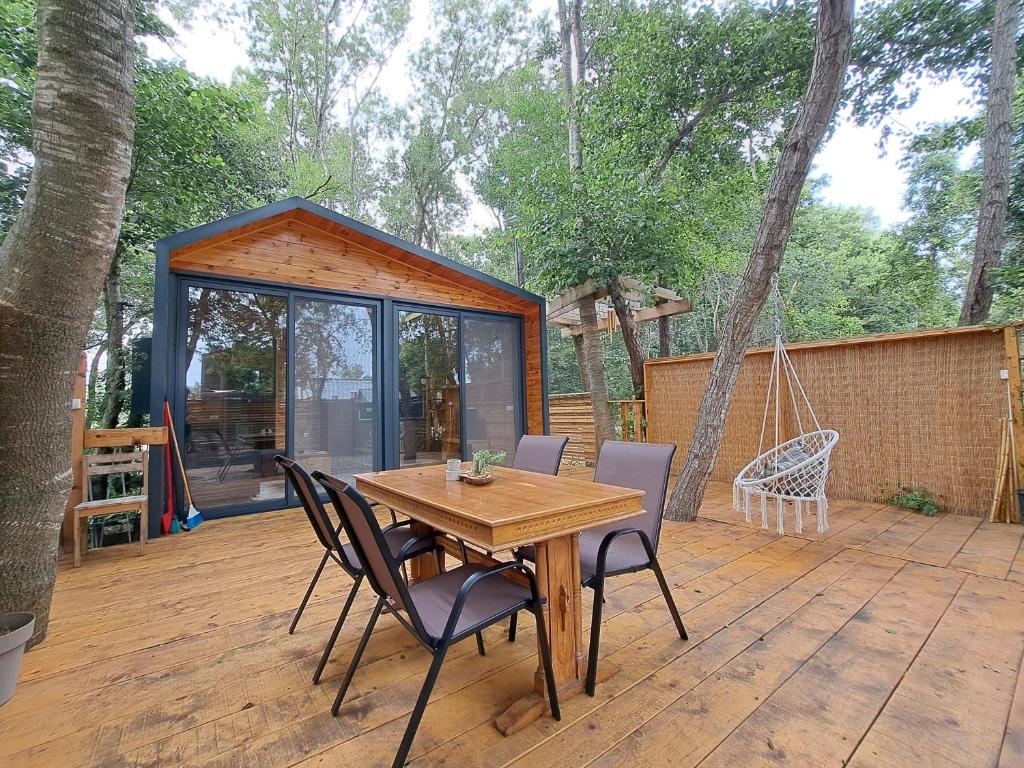 a wooden table and chairs on a deck with a house at Vista Cottage 2 in Ulcinj