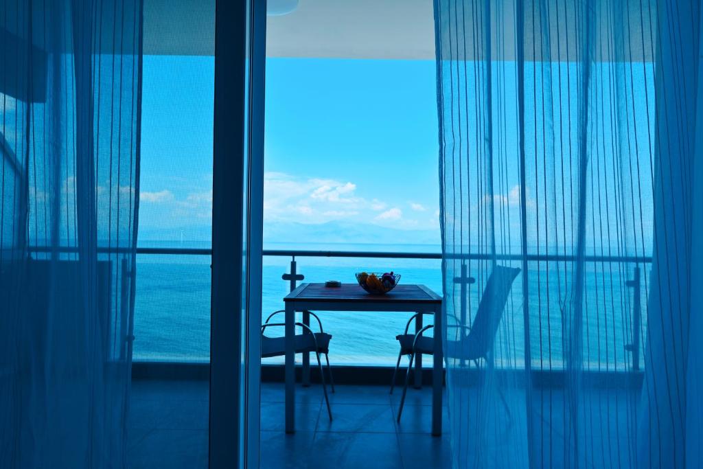 NEW TIMES SEAFRONT HOTEL APARTMENTS MELISSI في Melíssion: طاولة وكراسي في غرفة مطلة على المحيط