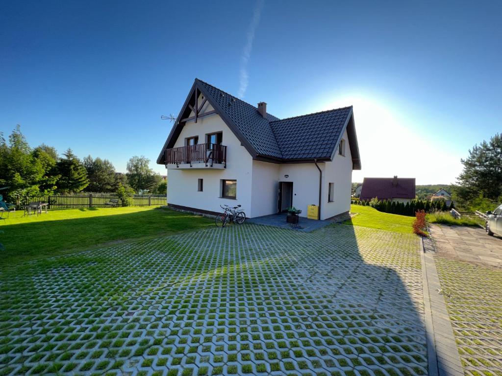 a white house with a black roof and a yard at Ginger Apartament in Wilkasy