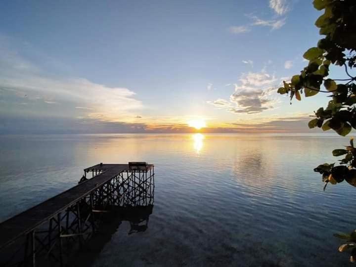 Maratua Dive Center And Lodge في Maratua Atoll: مرسى في وسط البحيرة مع غروب الشمس