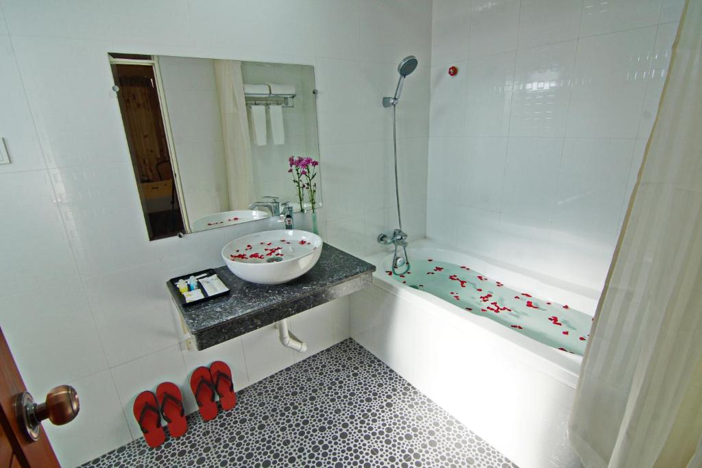 bagno con lavandino e vasca con specchio di Royal Pearl Hotel a Mandalay