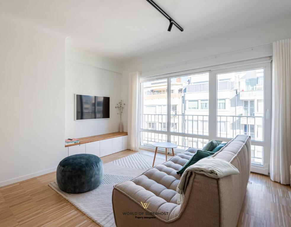 a living room with a couch and a large window at Luxurious apartment next to the sea and city centre with free parking space in Ostend