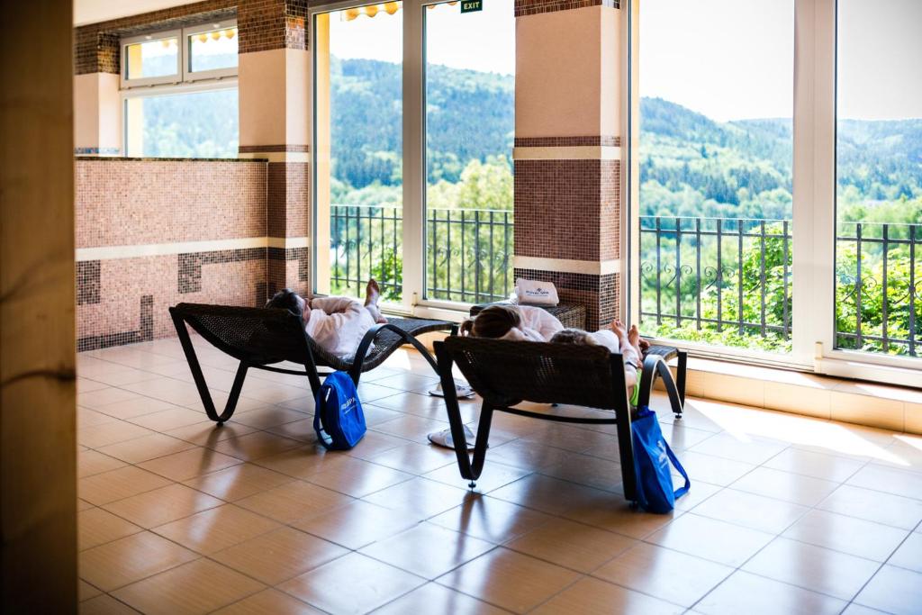 魯哈科維斯的住宿－Nivamare，两人坐在带阳台的房间的椅子上
