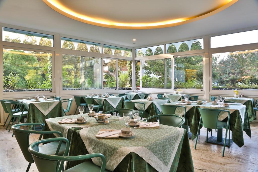 a dining room with tables and chairs and windows at Hotel Biasutti in Venice-Lido