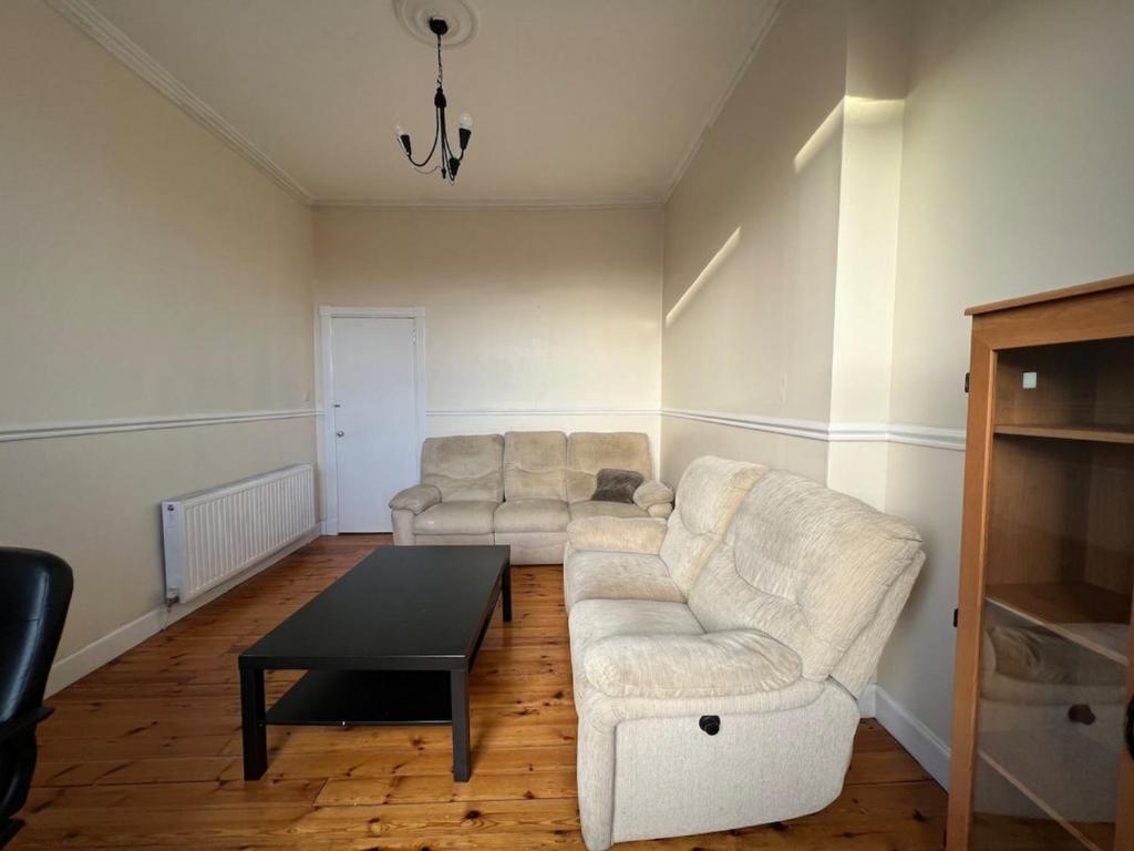 Lovely one bedroom Apartment in Glasgow City في غلاسكو: غرفة معيشة مع أريكة بيضاء وطاولة