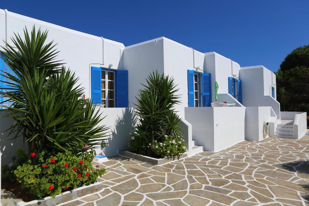 a row of white buildings with blue windows and plants at Fragos Apartments in Santa Maria