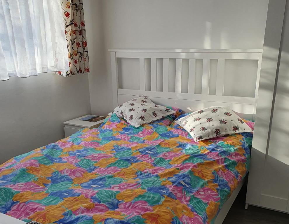 a bed with a colorful blanket and two pillows at ARANY13 Apartmanház - Mówimy po polsku! in Bogács