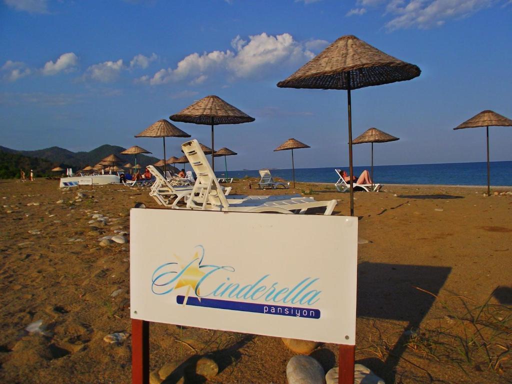 un cartel en una playa con sillas y sombrillas en Cinderella Pension & Bungalow en Cıralı