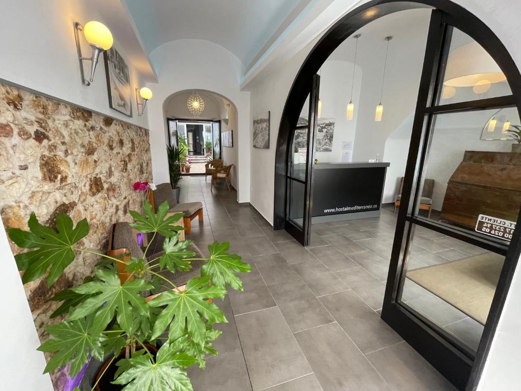 a hallway with a mirror and plants in a room at Hostal Mediterráneo in Tossa de Mar