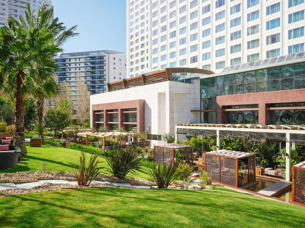 a park in front of a building with tall buildings at Corinthia Lisbon in Lisbon