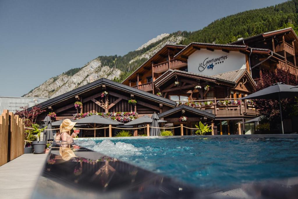 une femme assise dans une piscine devant un bâtiment dans l'établissement Les Gentianettes Hotel & Spa, à La Chapelle-dʼAbondance