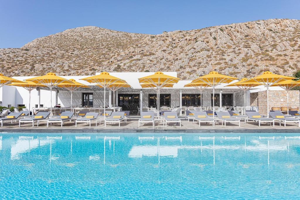 a swimming pool with yellow umbrellas and chairs at ANEMI Folegandros in Karavostasi