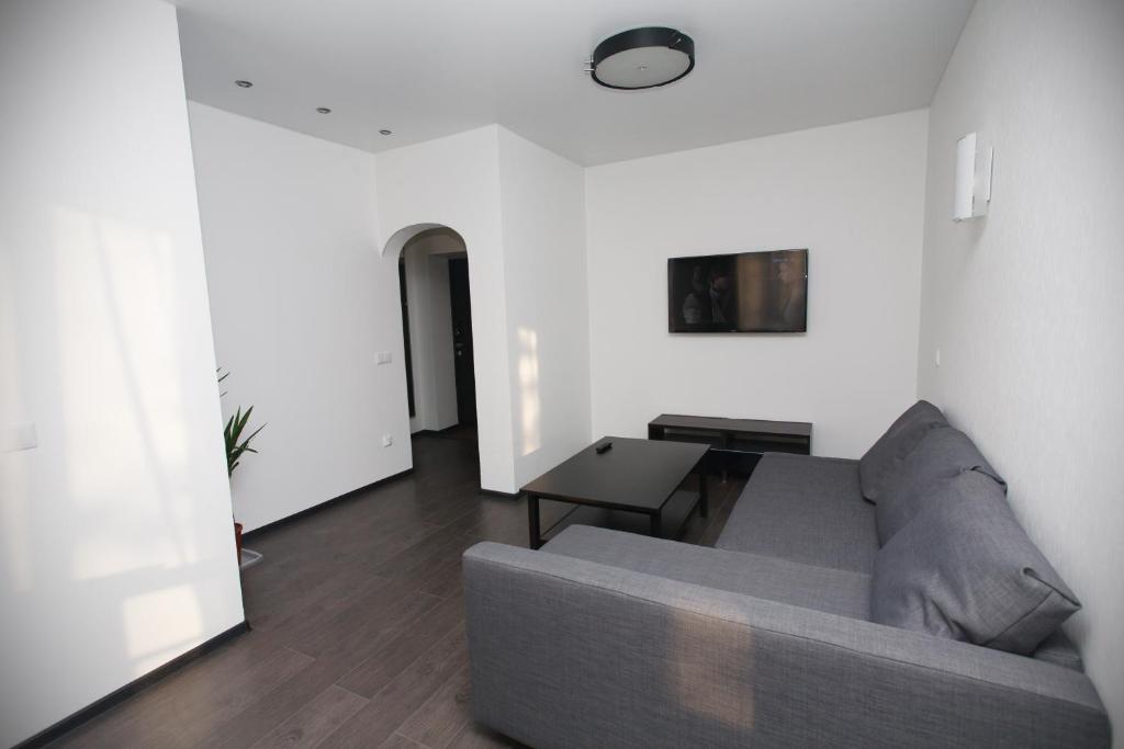 a living room with a gray couch and a table at Meretskova Apartment in Velikiy Novgorod