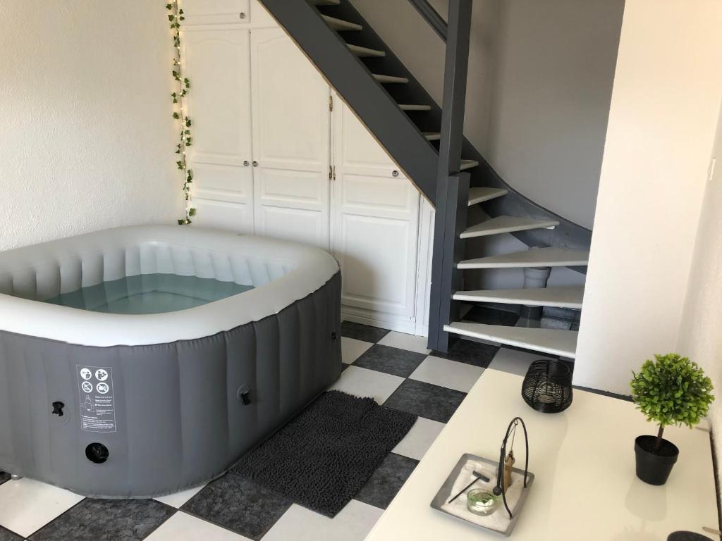 a bath tub in a room with a staircase at Le Clémenceau in Péronne