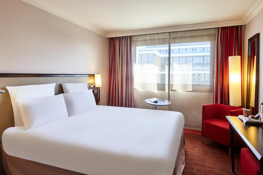 a hotel room with a bed and a red chair at B&B HOTEL Saint-Quentin-en-Yvelines Centre Gare 4 étoiles in Montigny-le-Bretonneux