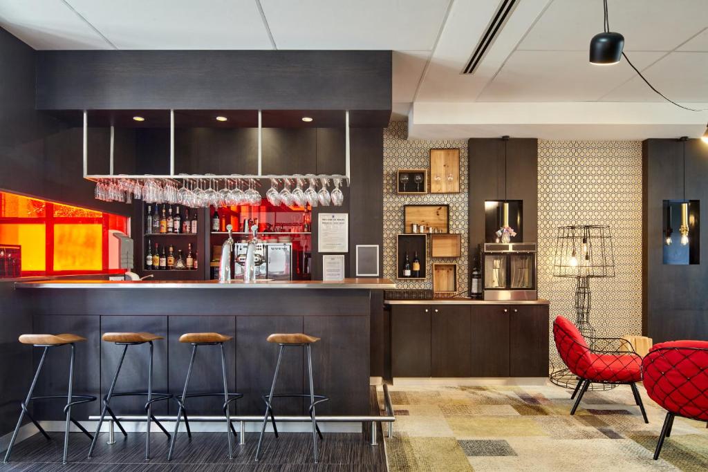 a bar in a restaurant with red chairs at B&B HOTEL Saint-Quentin-en-Yvelines Centre Gare 4 étoiles in Montigny-le-Bretonneux