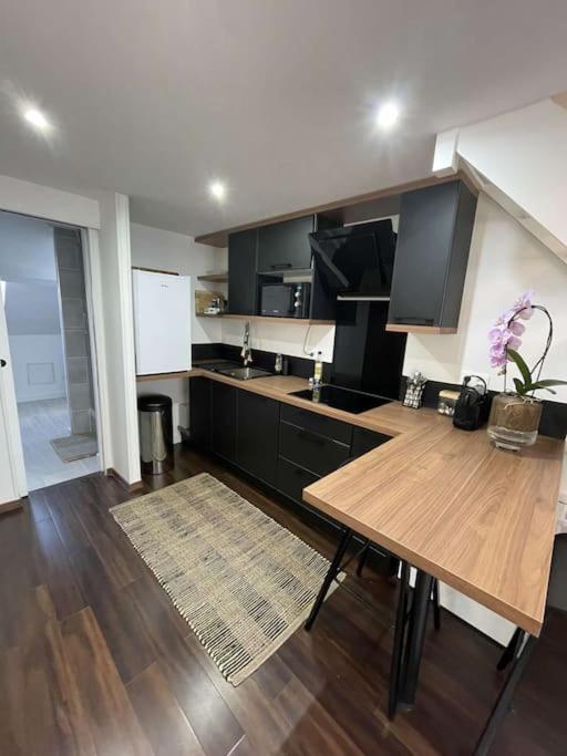 une cuisine avec une table en bois et des armoires noires dans l'établissement Jolie duplex - centre historique de Vannes, à Vannes